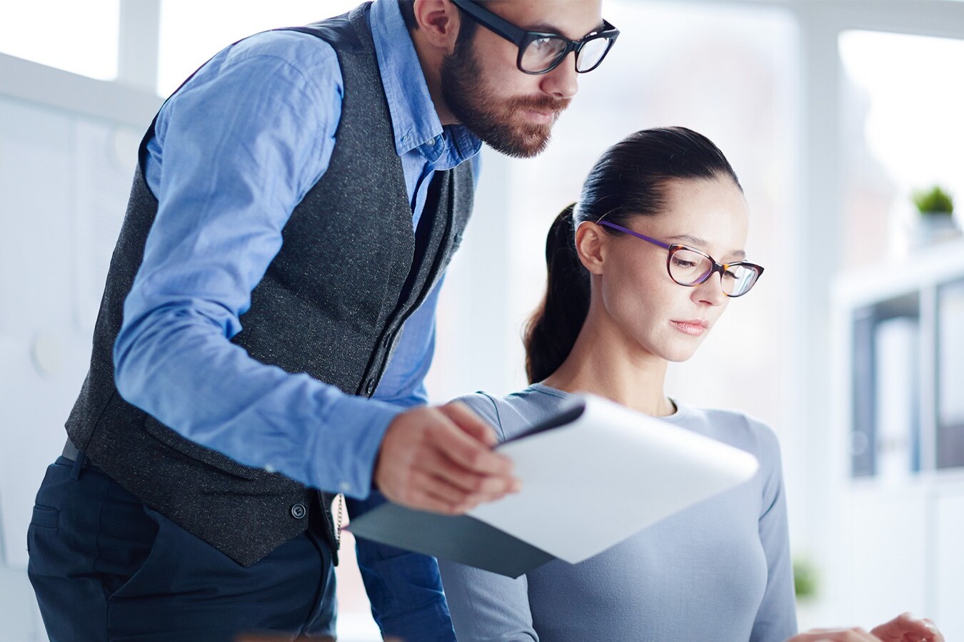 Colleague with a tablet supporting an employee at her workstation