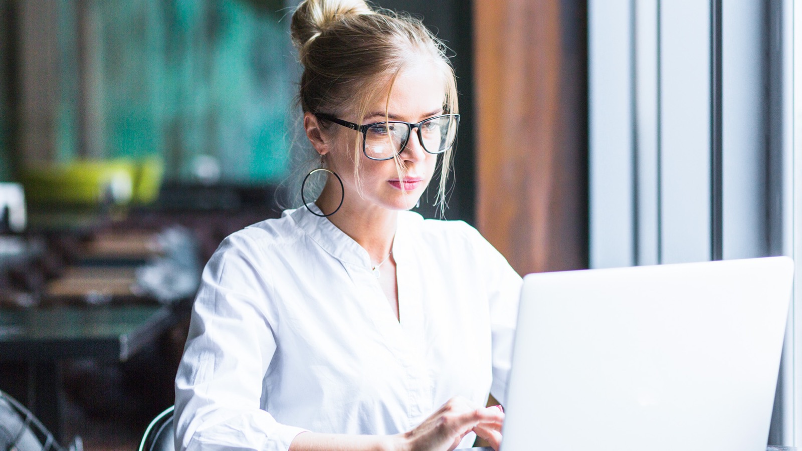 Employee with glasses working independently on her laptop